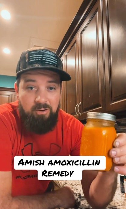 Milo holds a mason jar filled with an orange juice.