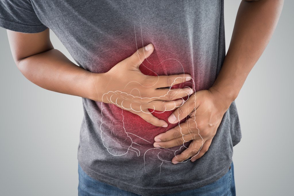 The man holding his belly against a gray background