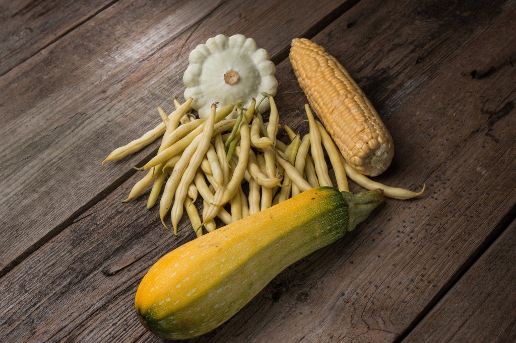 Green beans, corn and squash on the wooden table