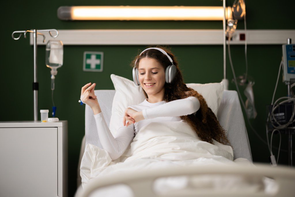 A patient in the hospital smiles while listening to music in bed.