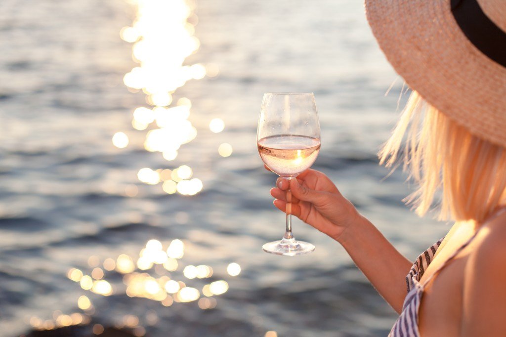 Woman drinks white wine from the ocean