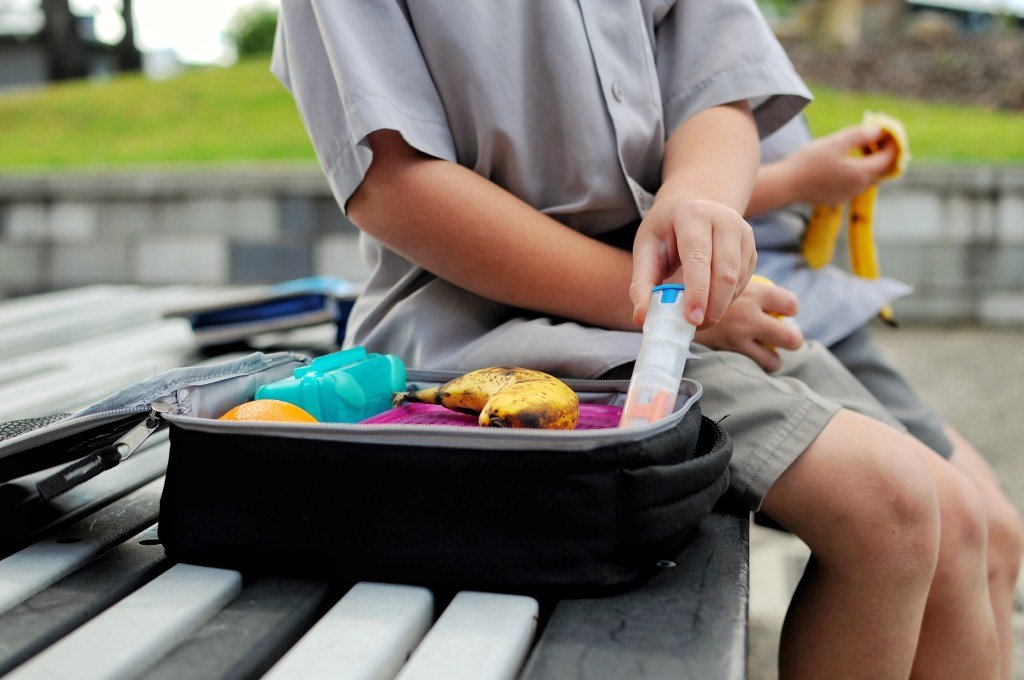 The boy opens the school's lunch, including his automatic anaphylaxis injector